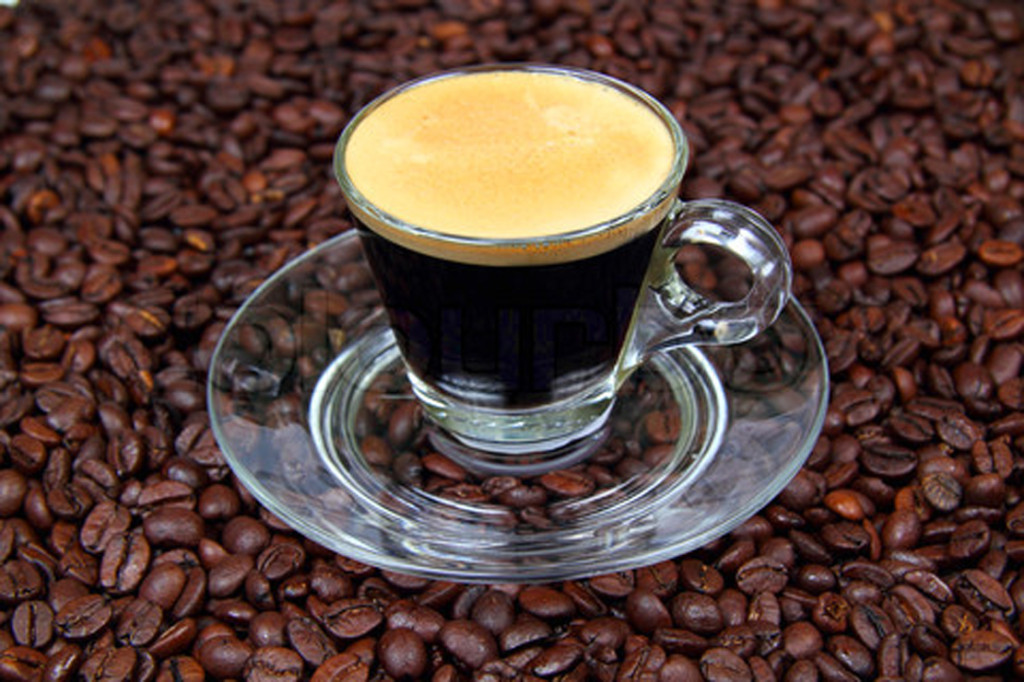 Espresso in a transparent cup on the background of coffee beans