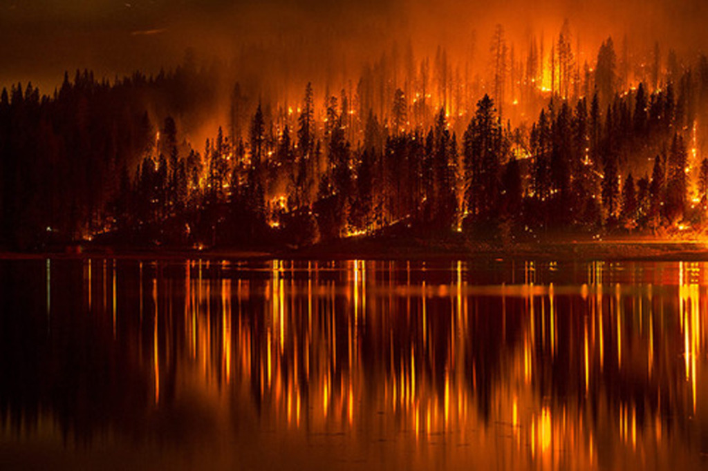 A fire approaches the shore of Bass Lake in California