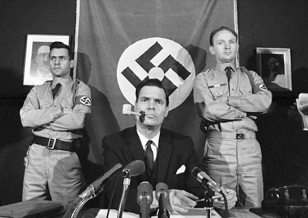 George Lincoln Rockwell, leader of the American Nazi Party holds a news conference in Arlington, Virginia, Nov. 3, 1965. Rockwell discussed the suicide in Reading, Pa., of Daniel Burros who was a member of Rockwell¬ís outfit and named by the House Committee on Un-American Activities as Ku Klux Klan leader in New York. Rockwell said ¬ìIf Burros had come and told me the truth I believe we could have straightened it out.¬î Burros killed himself after his Jewish heritage was disclosed. At left is Matt Koehl, and at right is Alan Welch, deputy commander. (AP Photo/Harvey Georges)